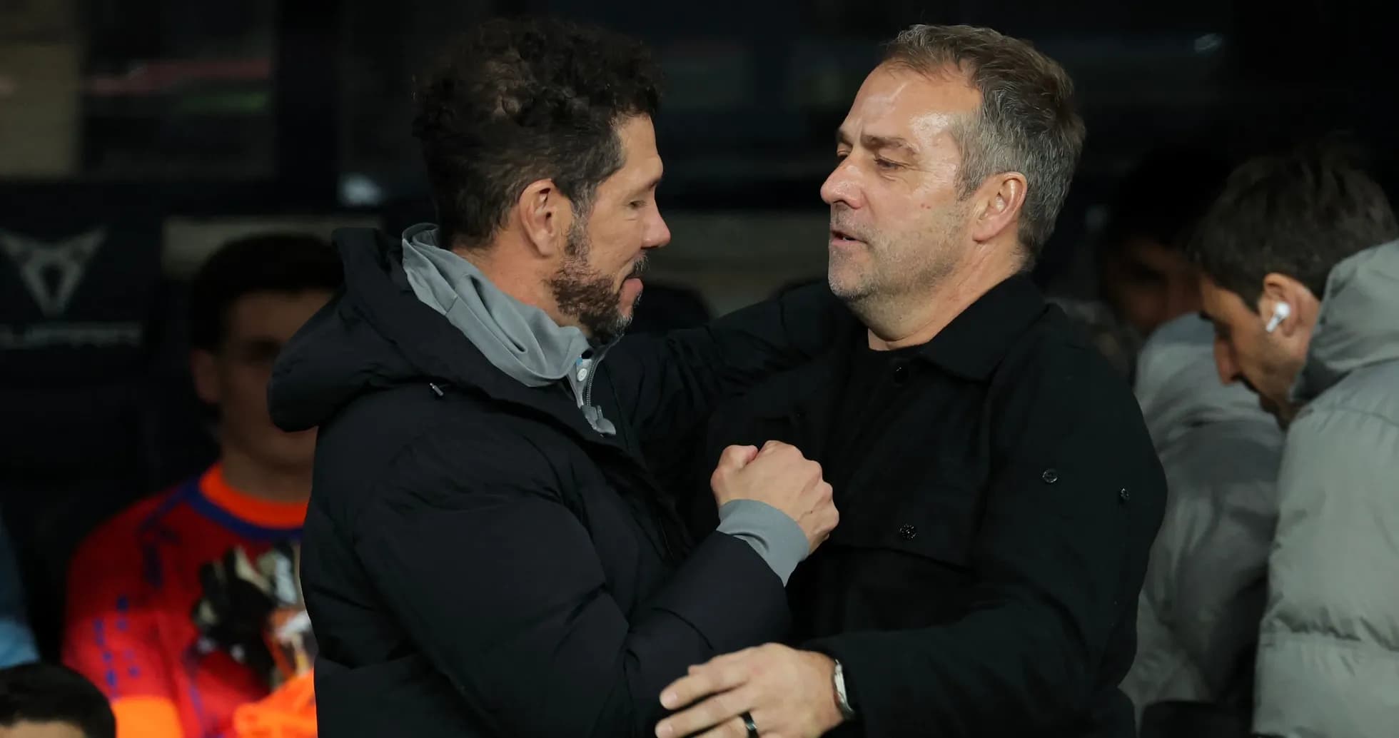 Entrenadores saludándose en el banquillo durante partido