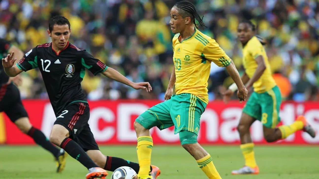 Jugador sudafricano esquivando a defensor mexicano en partido