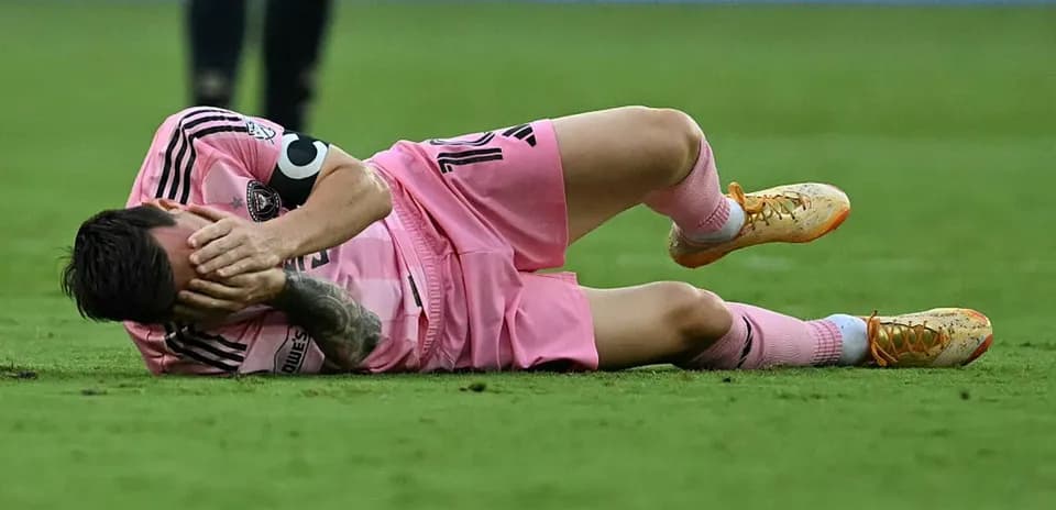 Jugador caído en el campo, sosteniendo su cabeza