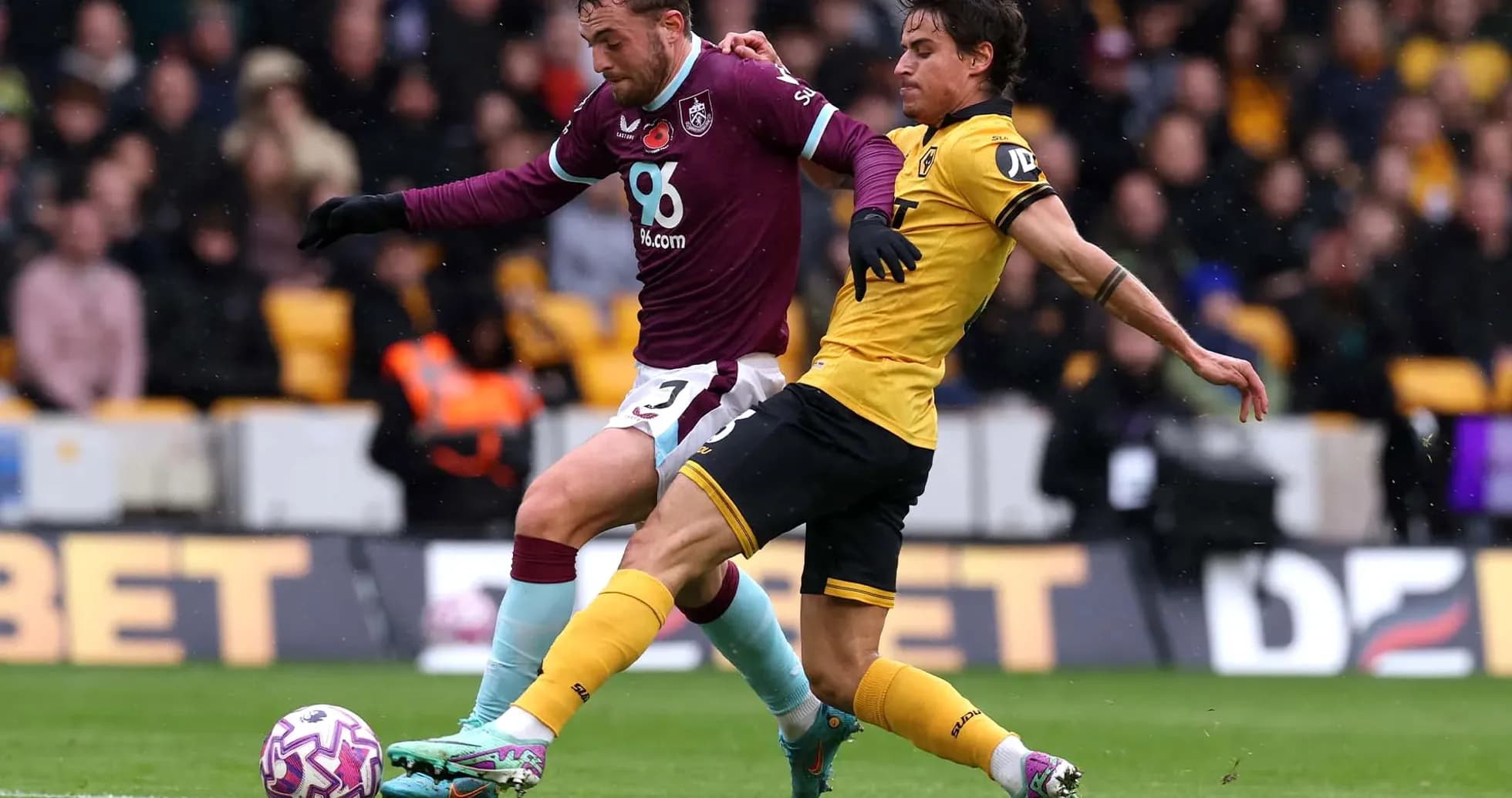 Jugador de Burnley compitiendo contra jugador de Wolves