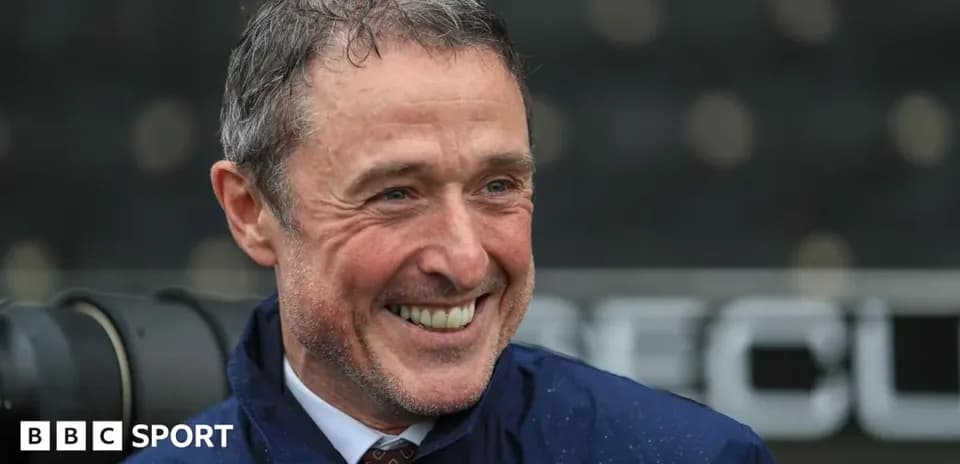 Entrenador sonriendo en la zona técnica del estadio