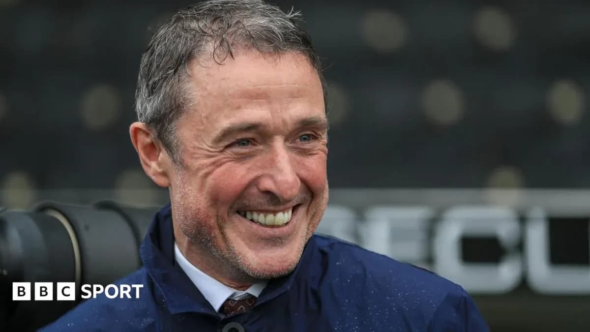 Entrenador sonriendo en la zona técnica del estadio