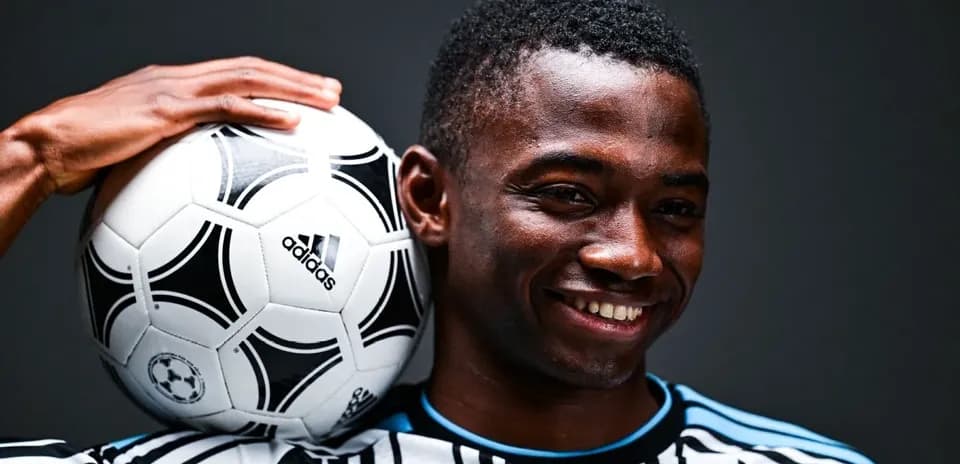 Jugador sosteniendo un balón de fútbol con sonrisa