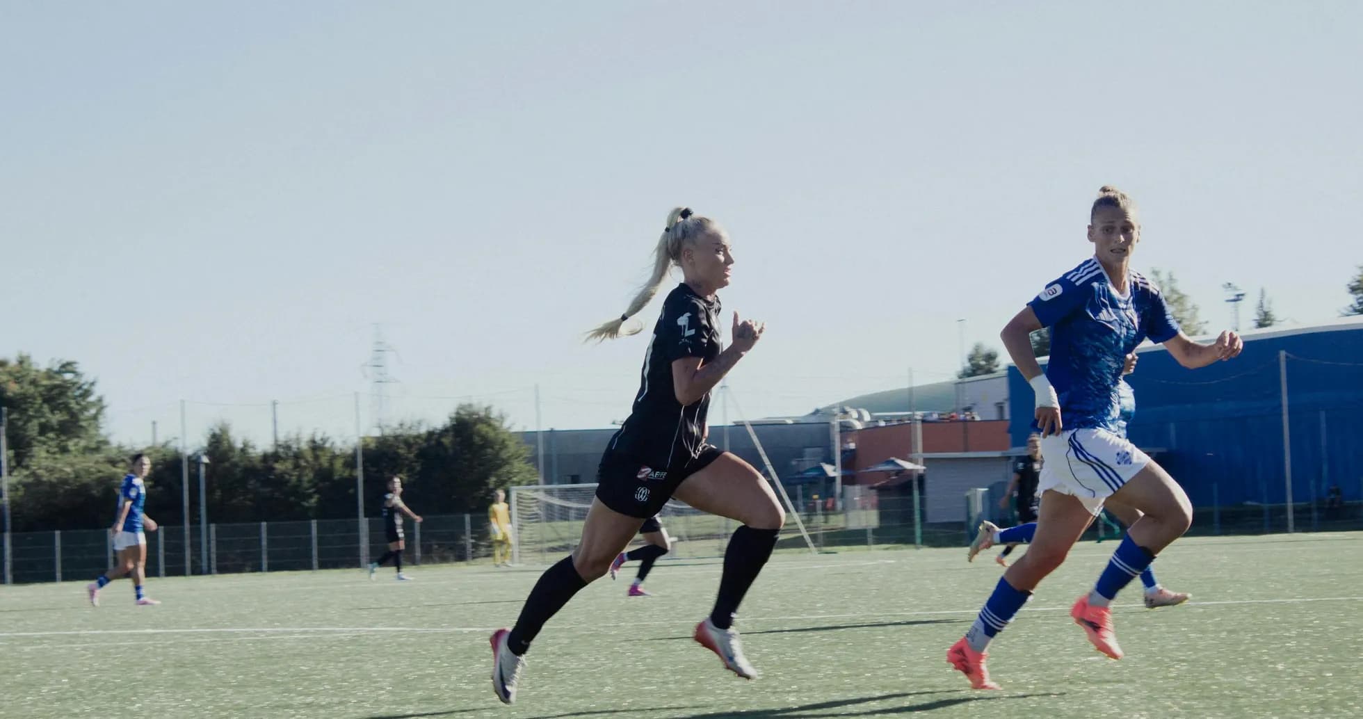Jugadoras corriendo en partido de fútbol femenino