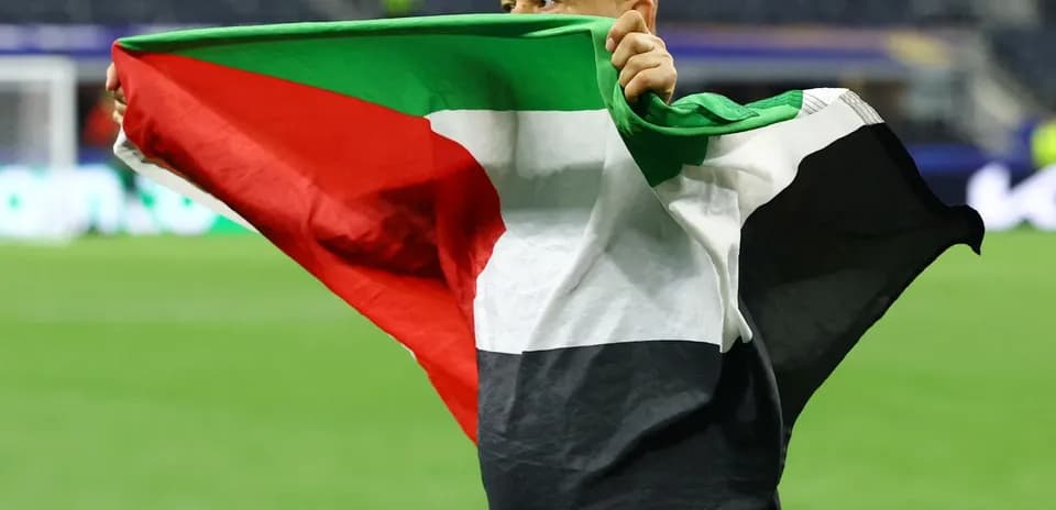 Hombre sosteniendo una bandera en el campo de fútbol