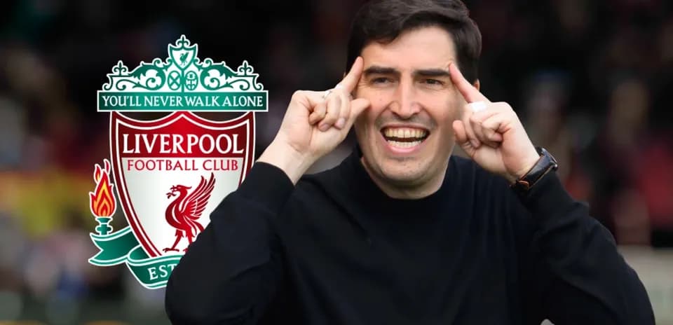 Entrenador sonriente junto al escudo de Liverpool