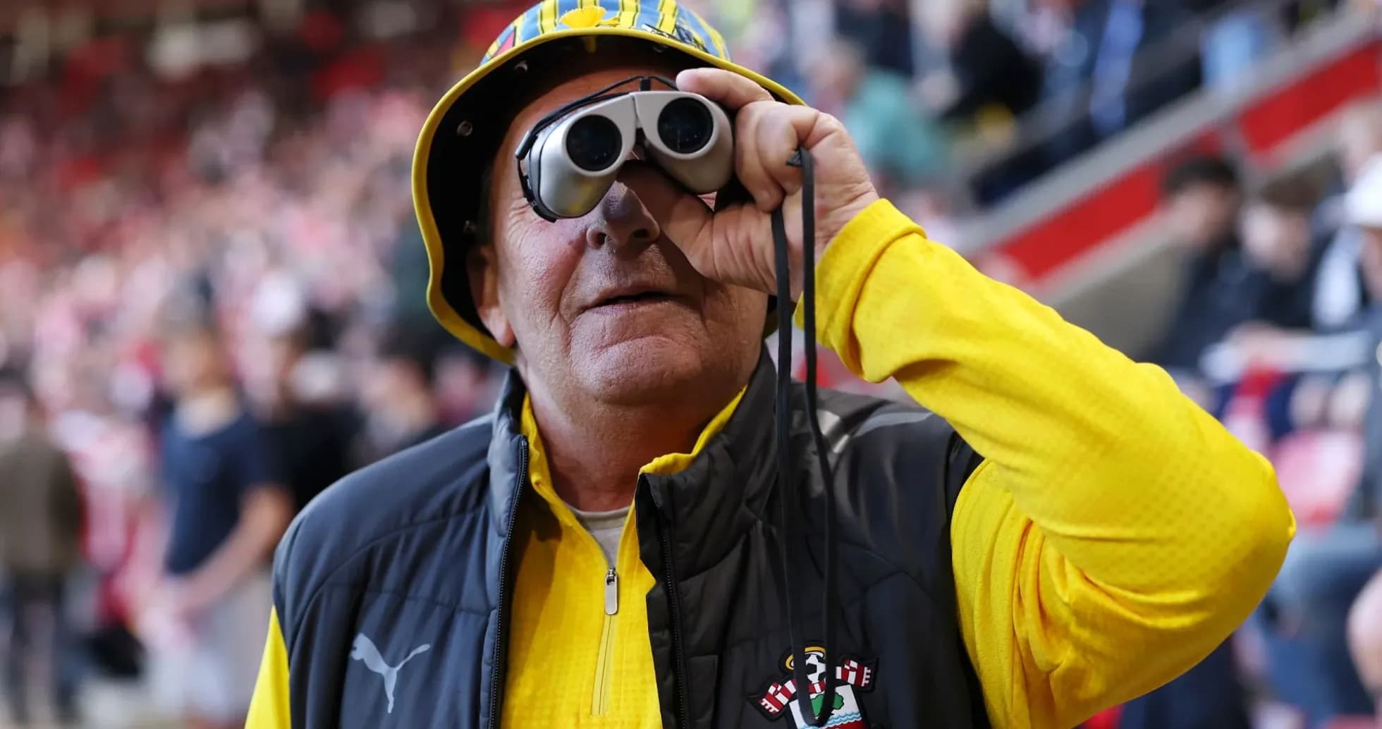 A fan wearing binoculars at a stadium