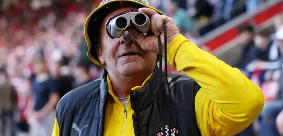 A fan wearing binoculars at a stadium
