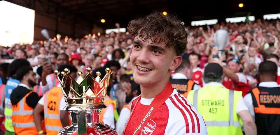 Jugador sosteniendo trofeo de la Premier League rodeado de aficionados