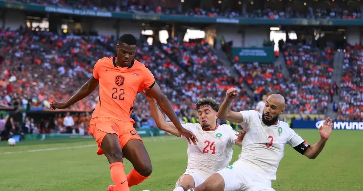 Jugador de Países Bajos driblando entre dos defensores marroquíes