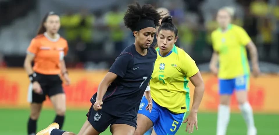 Jugadora de EE. UU. driblando ante defensora de Brasil