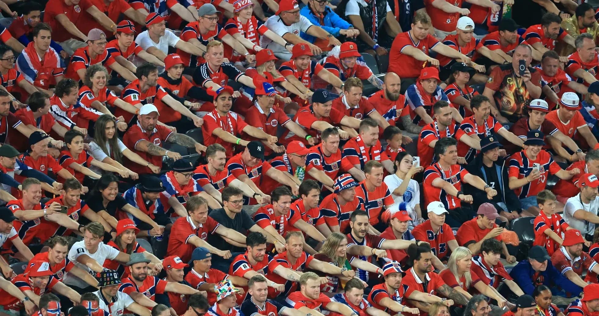 Aficionados animando en un estadio con camisetas rojas
