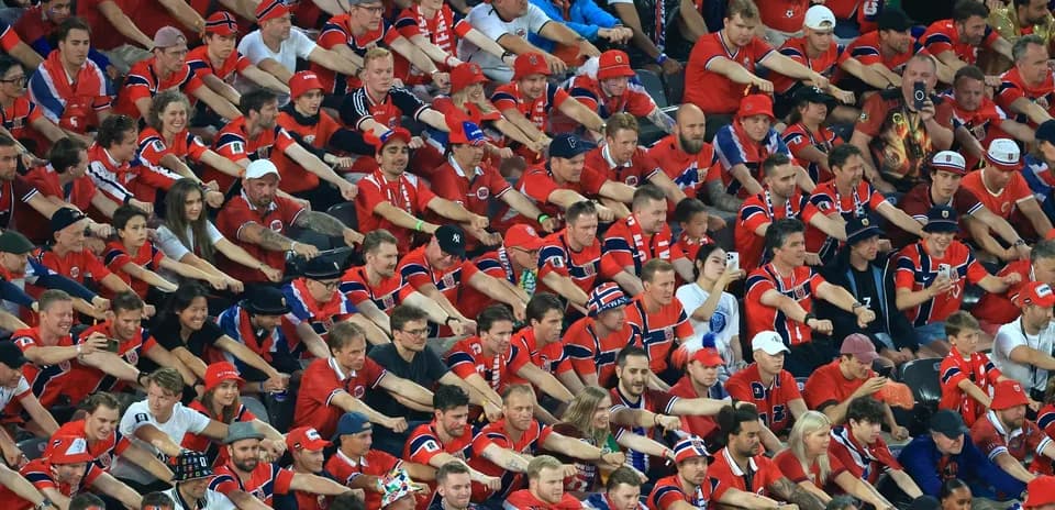 Aficionados animando en un estadio con camisetas rojas
