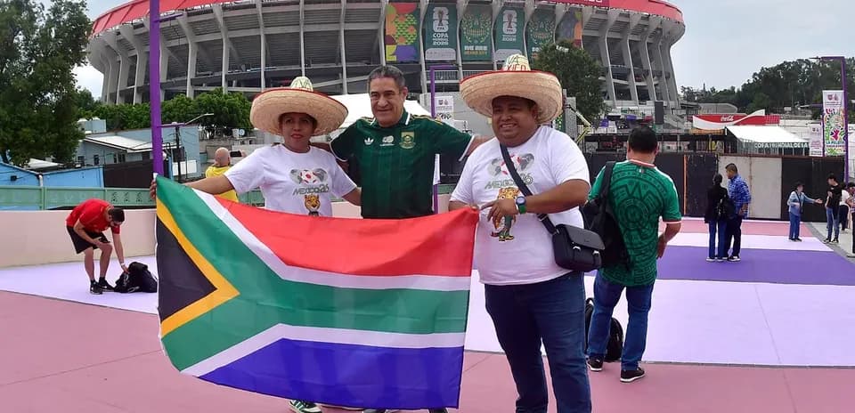 Tres aficionados con bandera de Sudáfrica en estadio