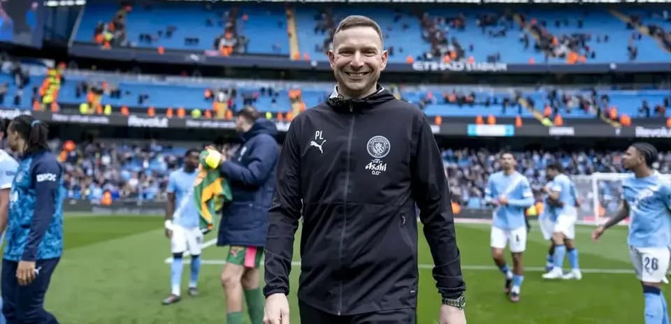 Entrenador sonriendo al salir del campo tras el partido