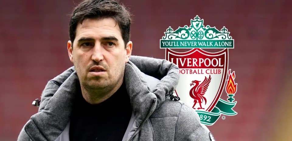 Entrenador con abrigo frente al escudo de Liverpool