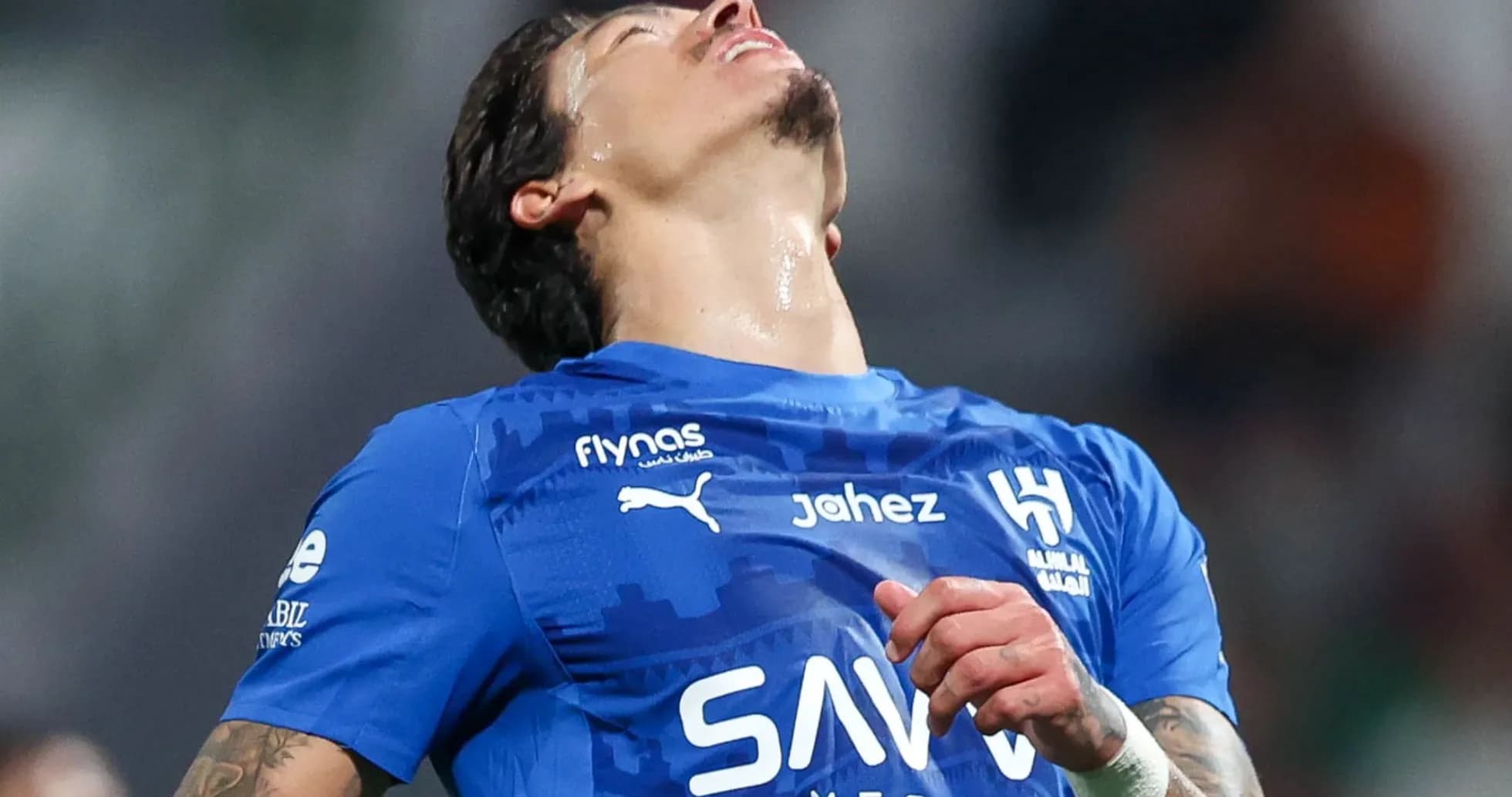 Jugador de fútbol en camiseta azul, mirando hacia arriba