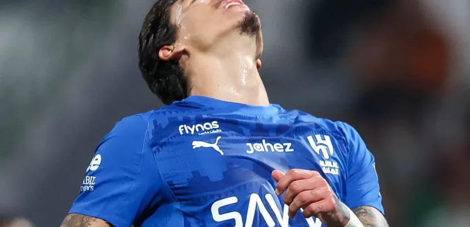 Jugador de fútbol en camiseta azul, mirando hacia arriba