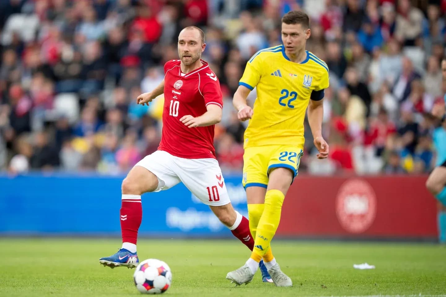 Jugador danés 10 persiguiendo al ucraniano 22 en partido