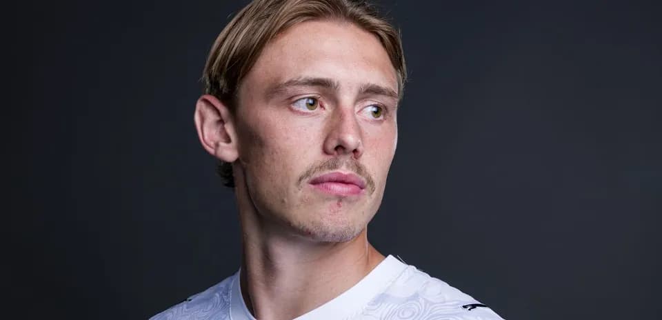 Jugador posando en camiseta blanca sobre fondo oscuro