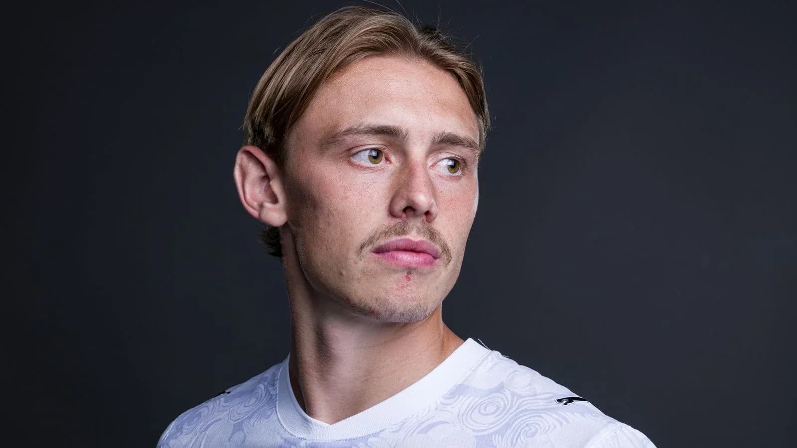 Jugador posando en camiseta blanca sobre fondo oscuro