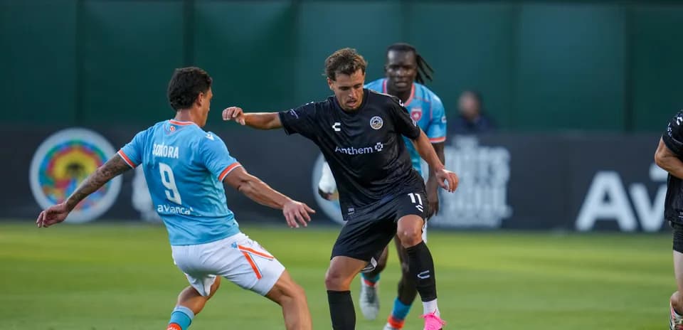 Jugador de Oakland Roots driblando a defensor