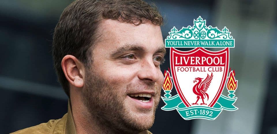 Hombre sonriendo junto al escudo del Liverpool FC