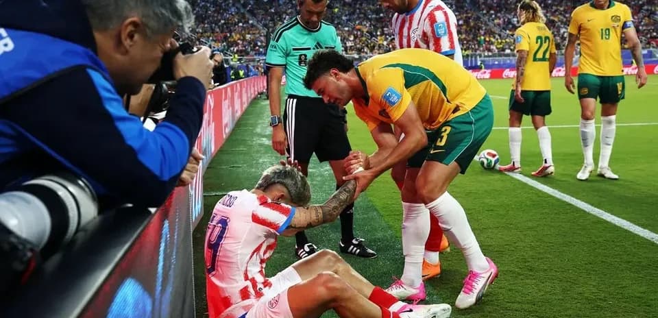 Jugador caído siendo atendido por rival y árbitro