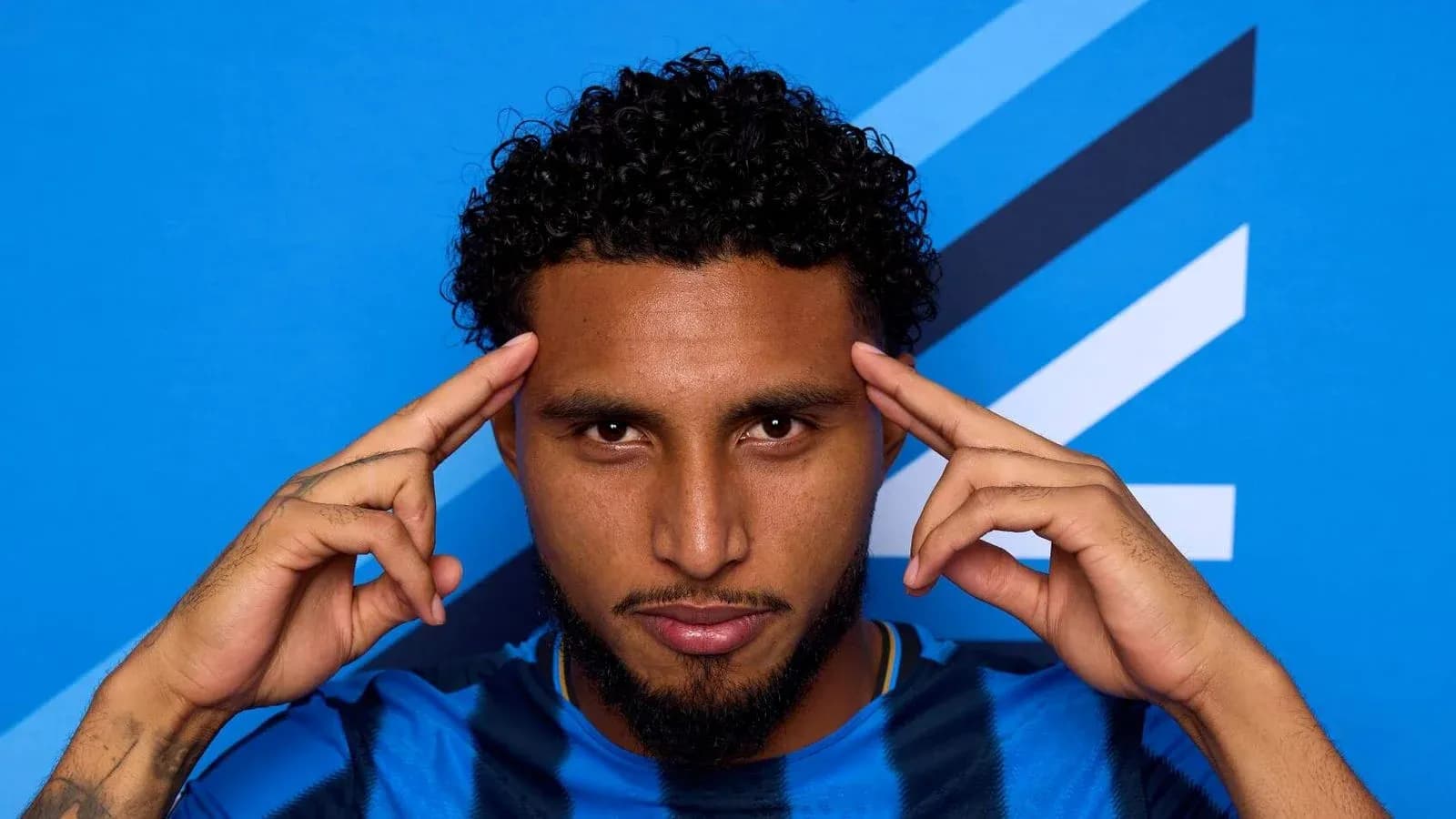 Jugador con camiseta azul posando frente fondo azul Jugador con camiseta azul posando frente fondo azul
