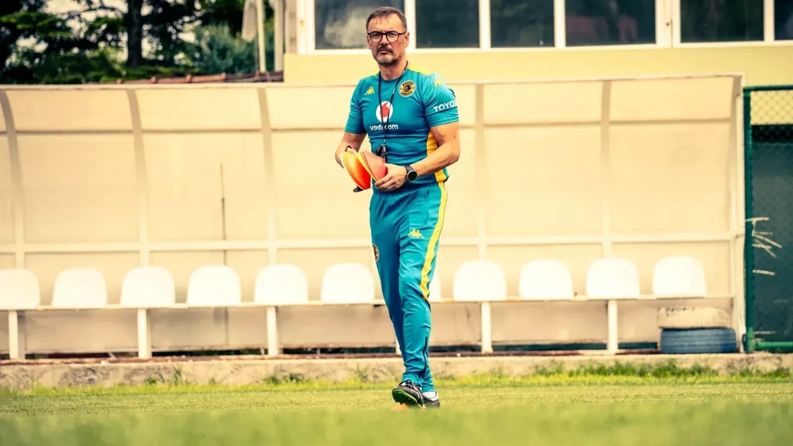 Entrenador caminando en el campo con conos Entrenador caminando en el campo con conos
